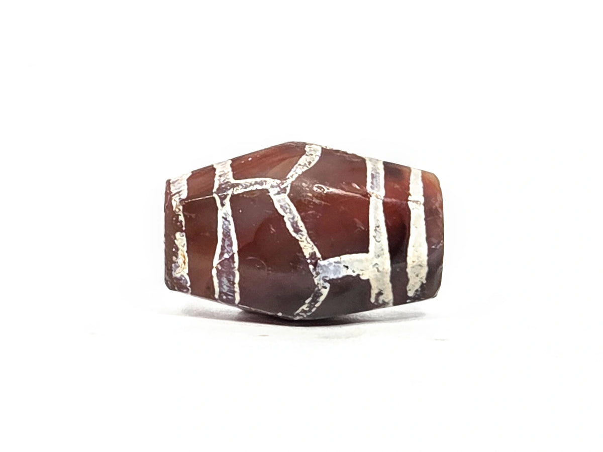 Third lateral profile of ancient etched carnelian longevity bead (AC-101026-CM2) showing further octagonal faces with white alkaline etching spread across deep reddish-brown and purple carnelian ground