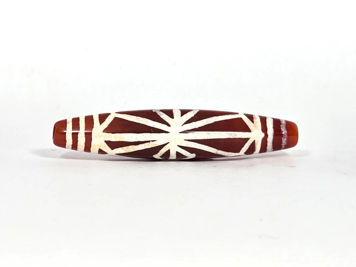 Ancient etched carnelian starburst bead AC-101026-CS, first lateral profile showing full radiating starburst motif within diamond frame and cream-white band lines on deep sienna carnelian, 500–700 years old