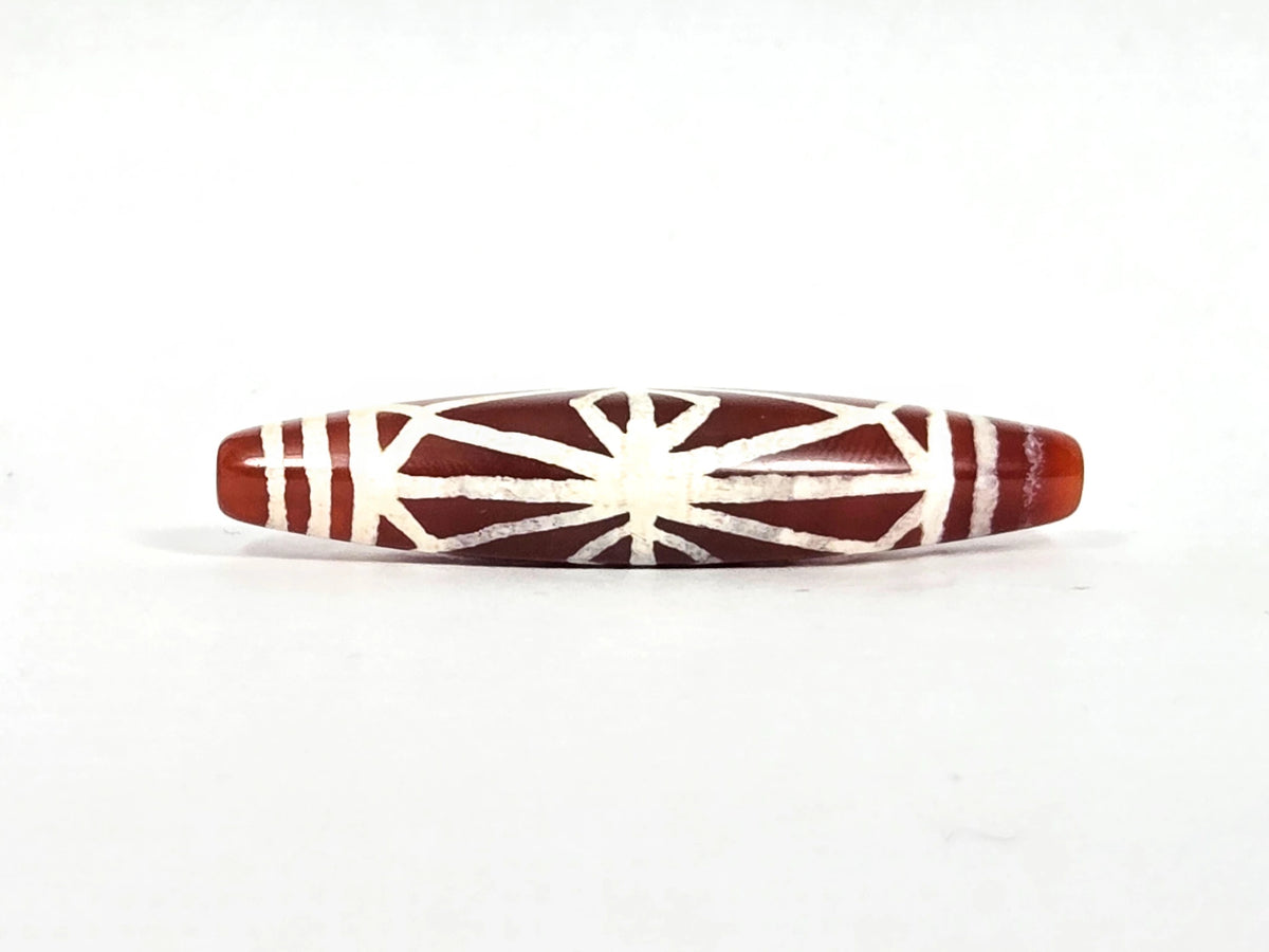Second lateral profile of ancient carnelian starburst bead showing reverse face with radiating lines, diamond lozenge frame, and horizontal end-cap band lines, 49.6 mm × 10.7 mm