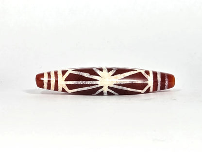 Third lateral profile of ancient etched carnelian starburst bead AC-101026-CS showing full spindle form, warm amber end caps, and complete cream-white starburst composition against deep sienna ground