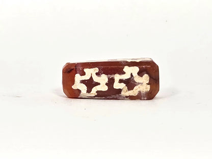 Second face of ancient carnelian eight-cross dzi bead showing two floriate cross motifs, thick cream-white alkaline etching on deep reddish-brown carnelian ground, 22.9 mm