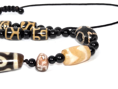 Seven-eye dzi bead necklace with tiger-skin agate, wave pattern focal, black onyx spacers, aged patina, visible drill holes