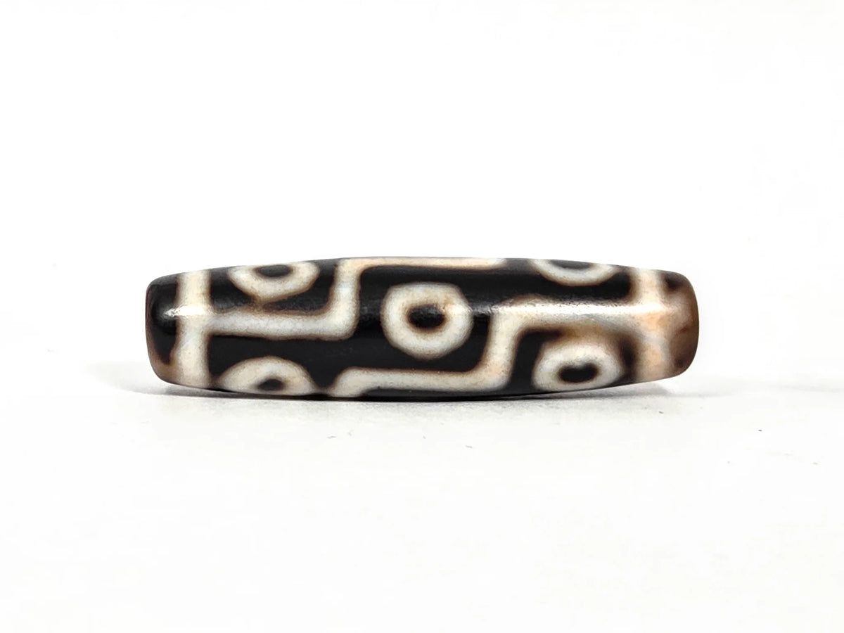 Second lateral profile of ancient nine-eye bloodspot dzi bead, reverse face showing symmetric eye pattern and aged brown-black agate surface, 45.5 mm