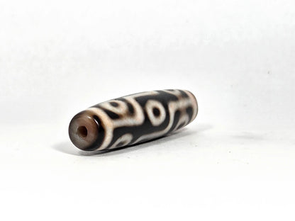 Opposite end view of ancient Tibetan nine-eye bloodspot dzi bead showing second drill hole aperture and warm brown agate end cap zone