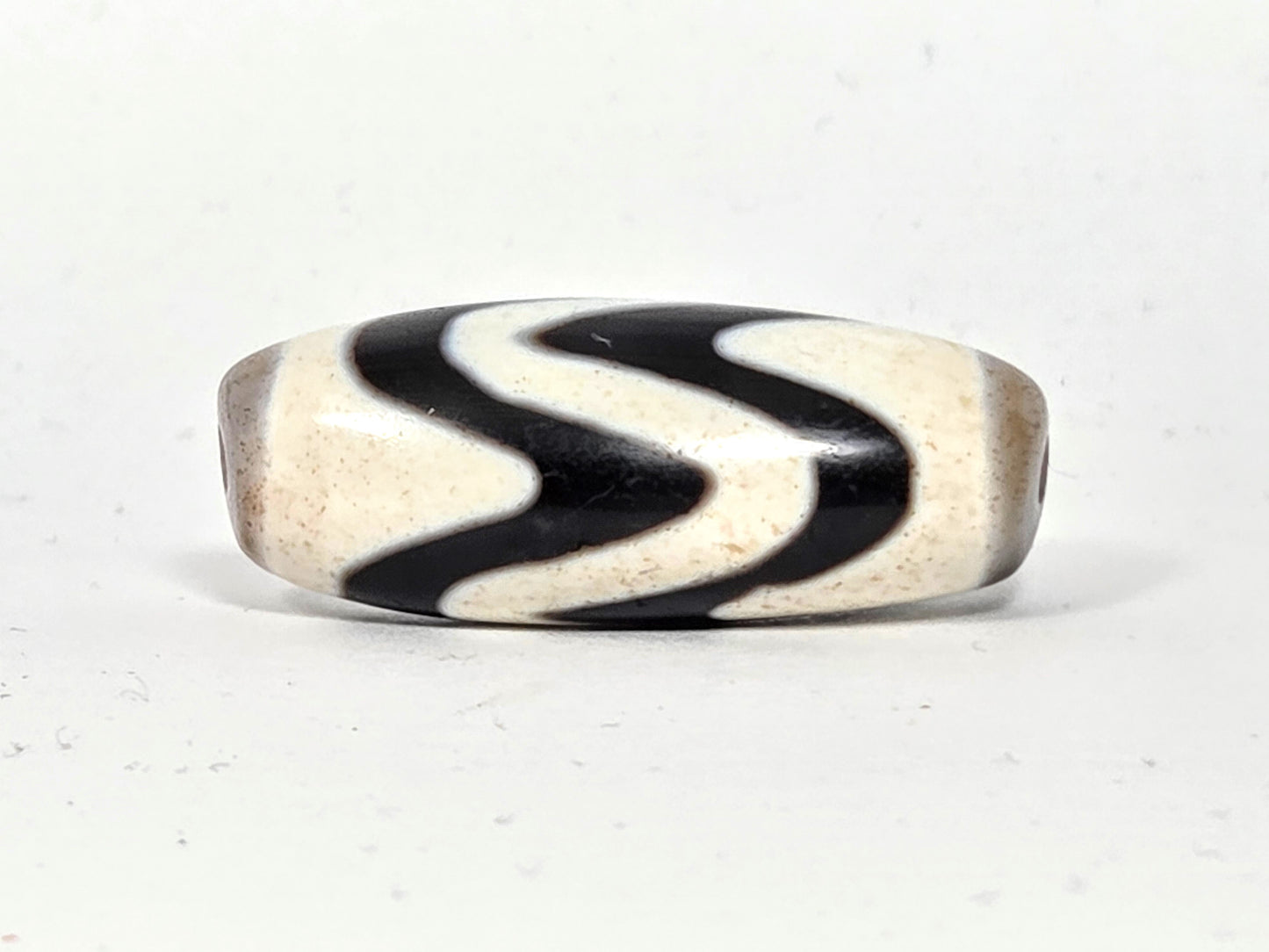 Ancient Tibetan Double Wave Dzi bead, 500–700 years old, 35.4mm — Side A showing strong S-curve wave pattern, natural black and ivory agate — unretouched photo — Ancient Dzi Shop