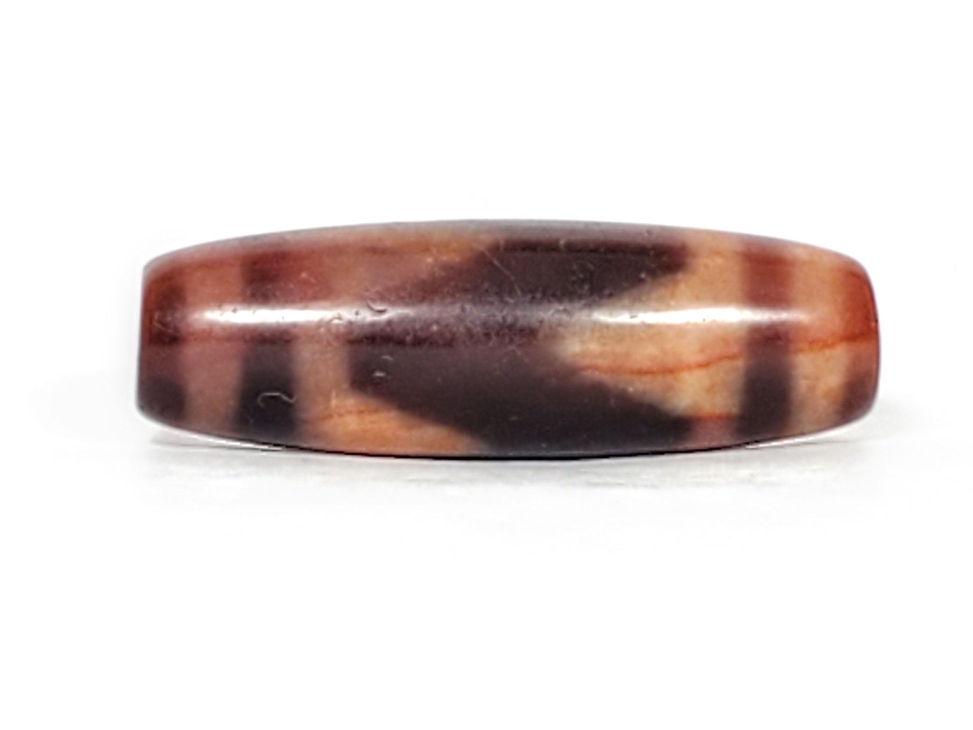 Third face of ancient Tasso Dzi bead — dark mahogany zone with cream Tasso forms, 500–800 years old