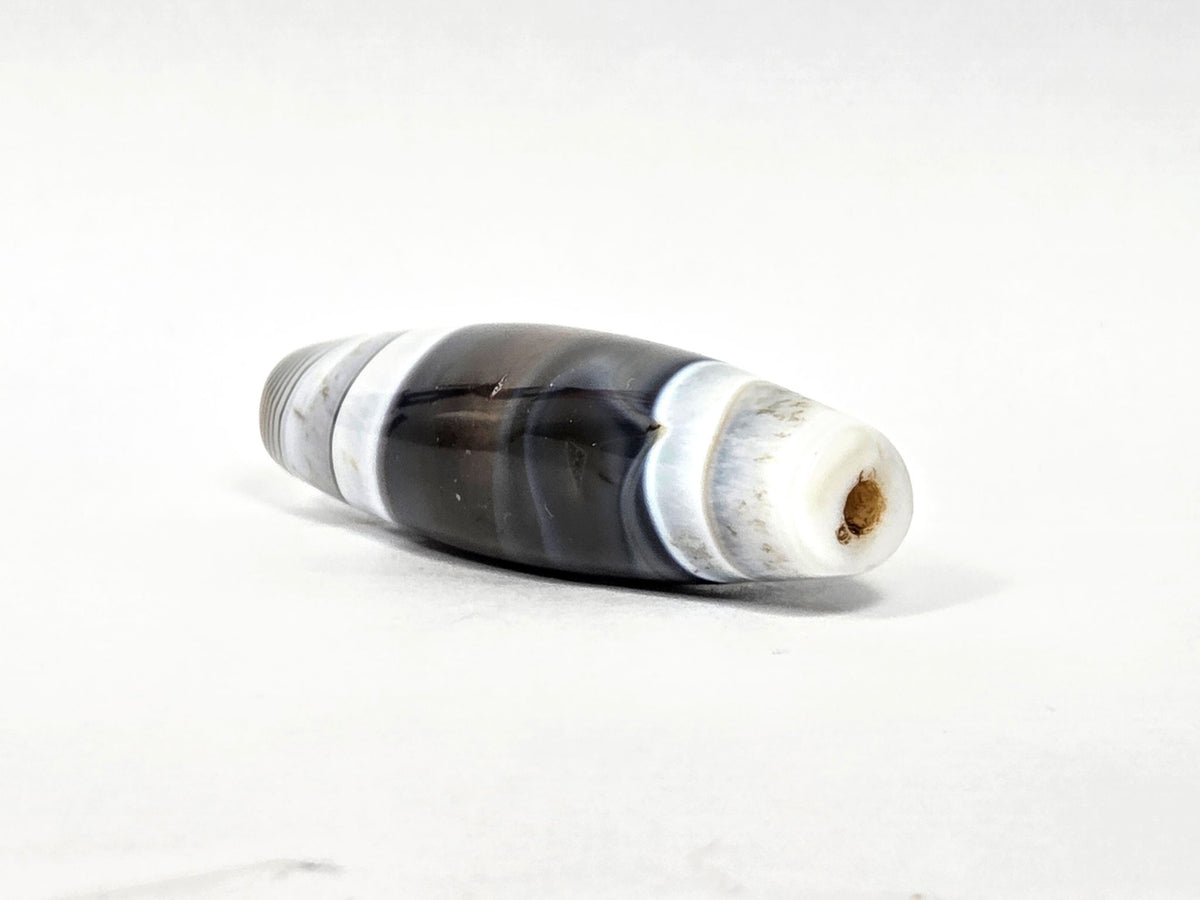At-N-071426-NBA end angle B — narrower tapered end, dense concentric agate rings, drill opening visible, unretouched.
