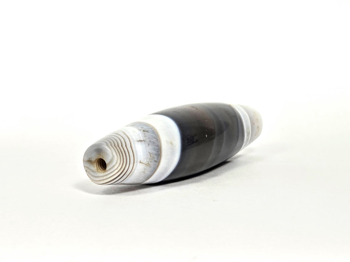 At-N-071426-NBA end angle A — wider end cap, concentric micro-banding, brown drill channel patina, unretouched.