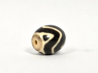 At-080926-WTT antique round Wave Tiger Tooth dzi bead 17.8×15.6mm, side rotation showing sinuous wave lines and cream drill-end cap on very dark brown ground, unretouched