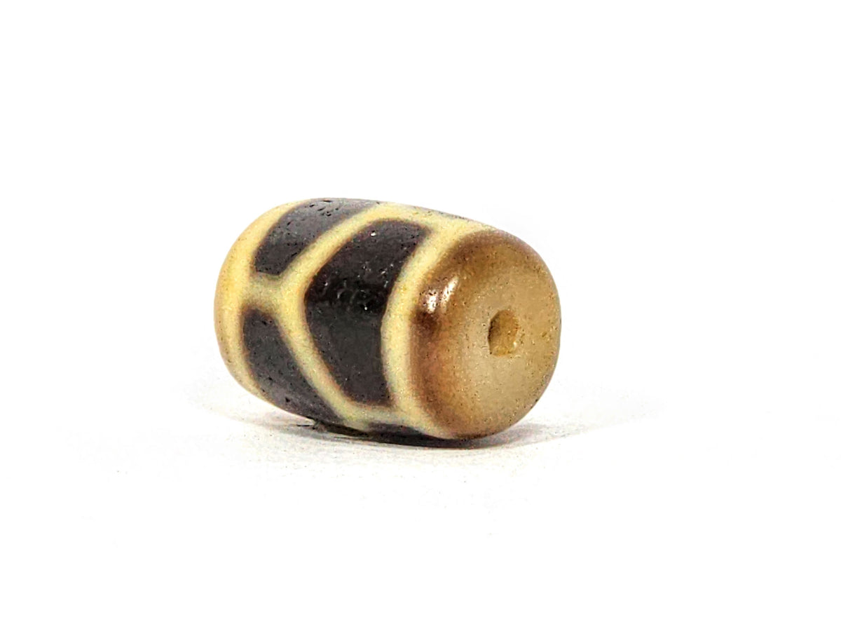 Antique dzi bead longevity motif, cream and dark brown agate, barrel shape, visible drill hole, aged patina surface