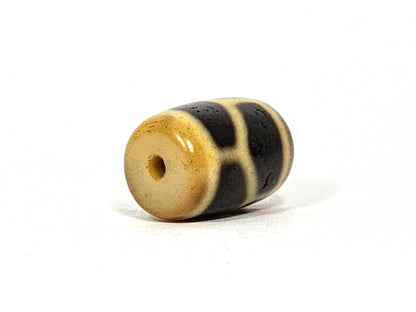 Antique longevity dzi bead, cream and black agate, barrel-shaped, cross motif on end, visible drill hole, aged patina