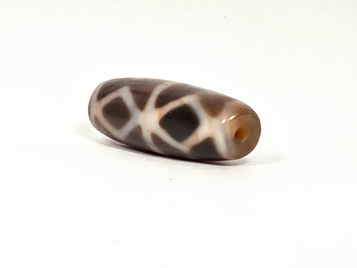 At-080926-6EDS2 antique Six Eye Diamond Spear dzi bead 33.0×11.5mm, opposite angled drill-end view showing warm translucent agate tip and diamond motif body, unretouched