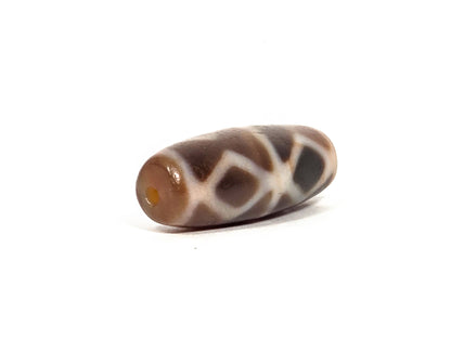 At-080926-6EDS2 antique Six Eye Diamond Spear dzi bead 33.0×11.5mm, angled drill-end view showing warm honey agate channel and diamond lines wrapping to end, unretouched