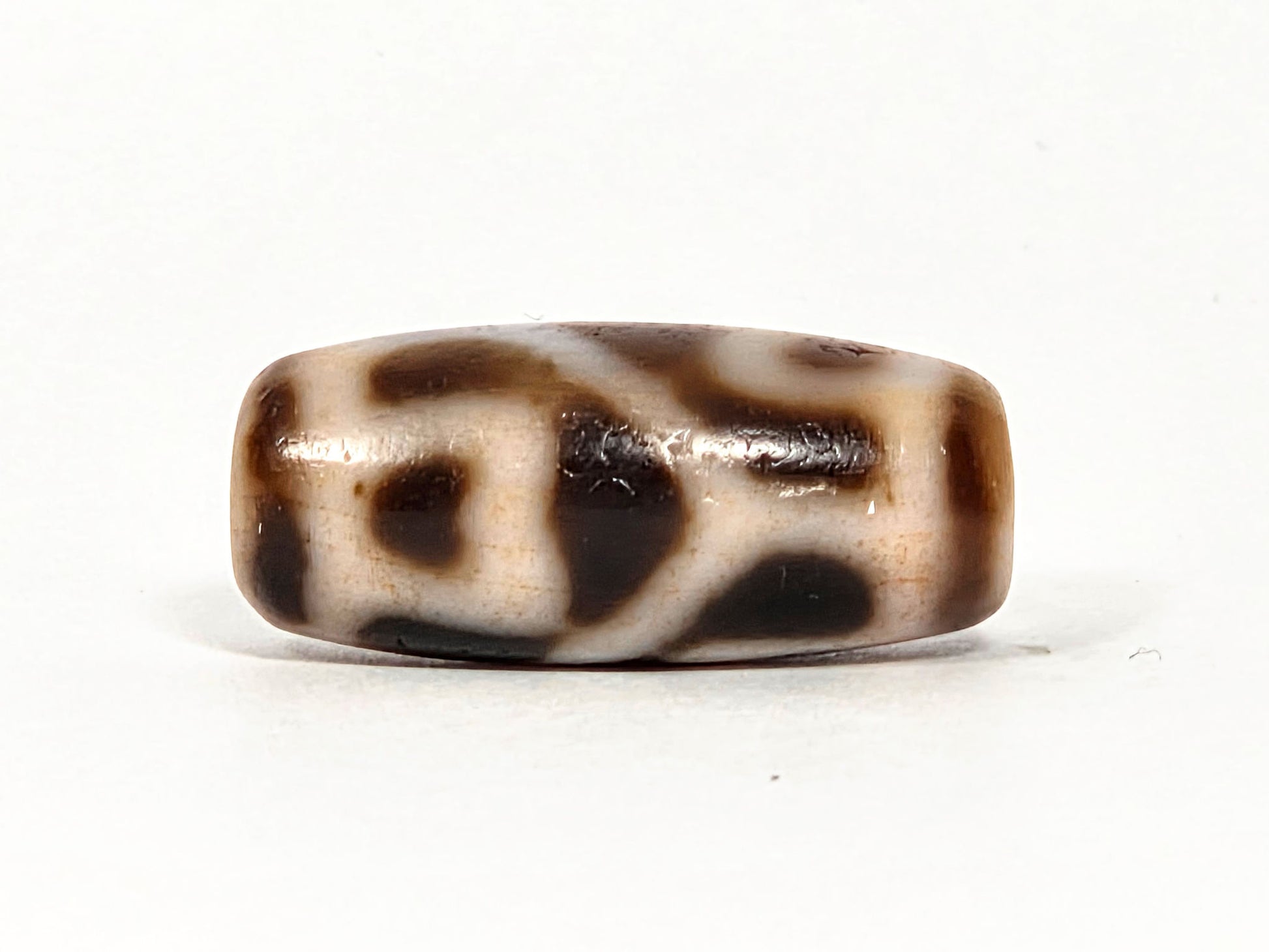 At-080926-6ELCBS antique Six Eye Lotus Cross dzi bead 24.1×10.8mm, Face C turn showing bracket element, connecting bar, and large oval on cream ground, unretouched