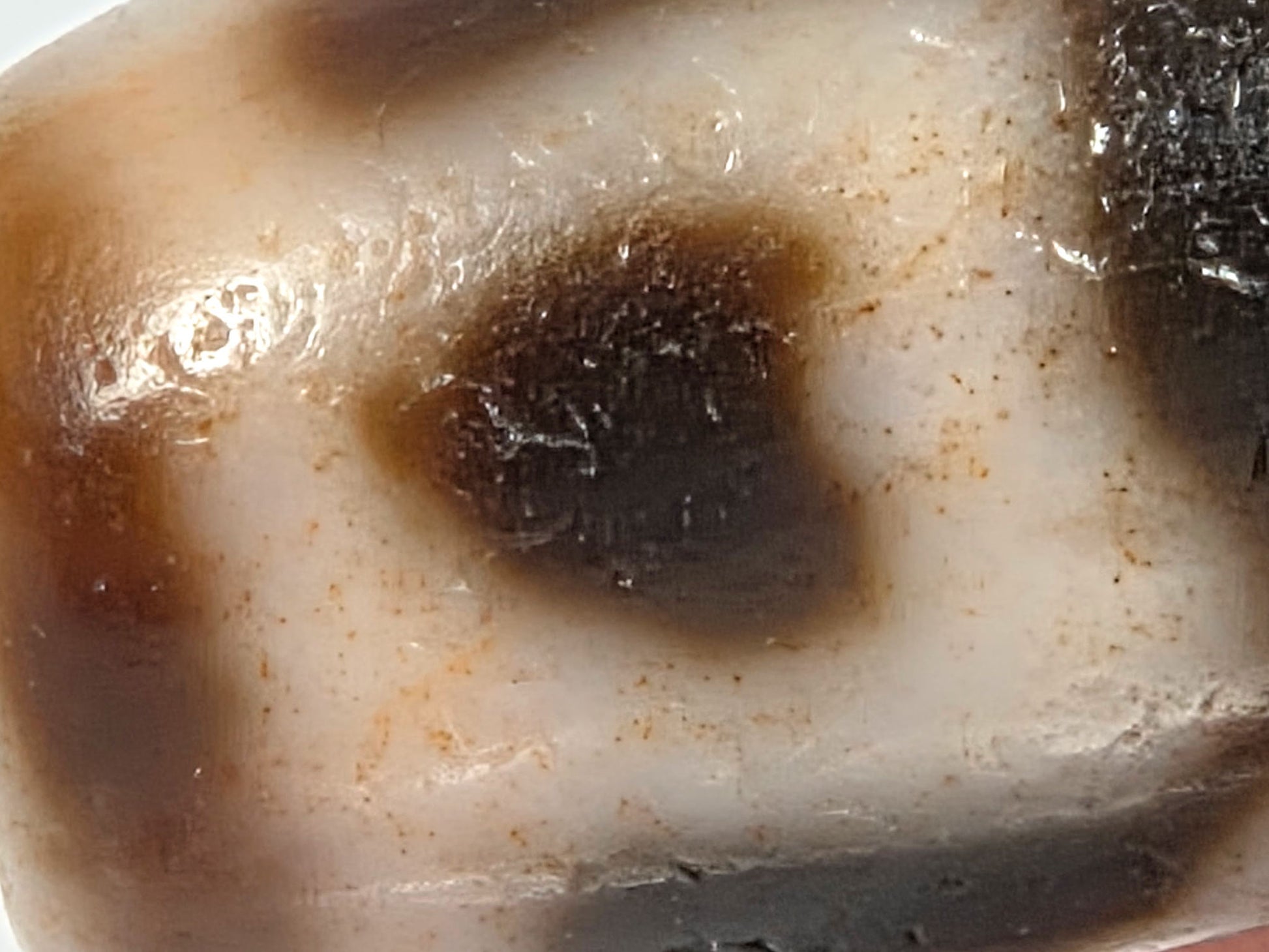 At-080926-6ELCBS macro view showing boundary-concentrated cinnabar dot scatter around dark oval motif form, age-crystalline surface texture throughout, unretouched