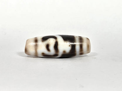 Third lateral profile of antique Tibetan dzi bead AT-B-101226-TLV showing full flat disc-barrel form, dark brown flowing motif lines, and cream-white agate with bloodspot patina, 200–300 years old