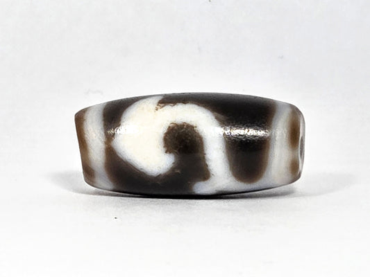 At-080926-RuyiBS antique Ruyi dzi bead 26.2×12.0mm, Face A showing large cream scroll cloud-head sweeping against very dark brown ground, unretouched