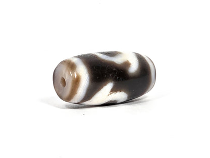 At-080926-RuyiBS antique Ruyi dzi bead 26.2×12.0mm, opposite angled drill-end view showing cream end cap with warm tan ring around drill hole, unretouched