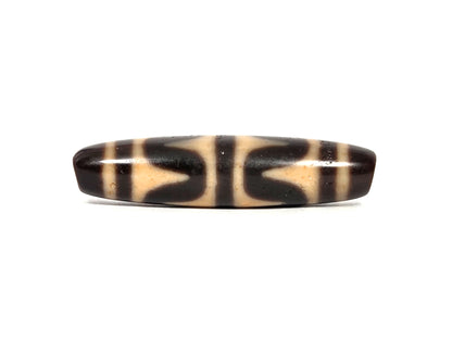 Antique Tibetan double wave dzi bead (AT-092926-DW4), first lateral profile showing dark brown and black opposing wave forms on honey-tan agate ground, 49.7 mm, 200–400 years old