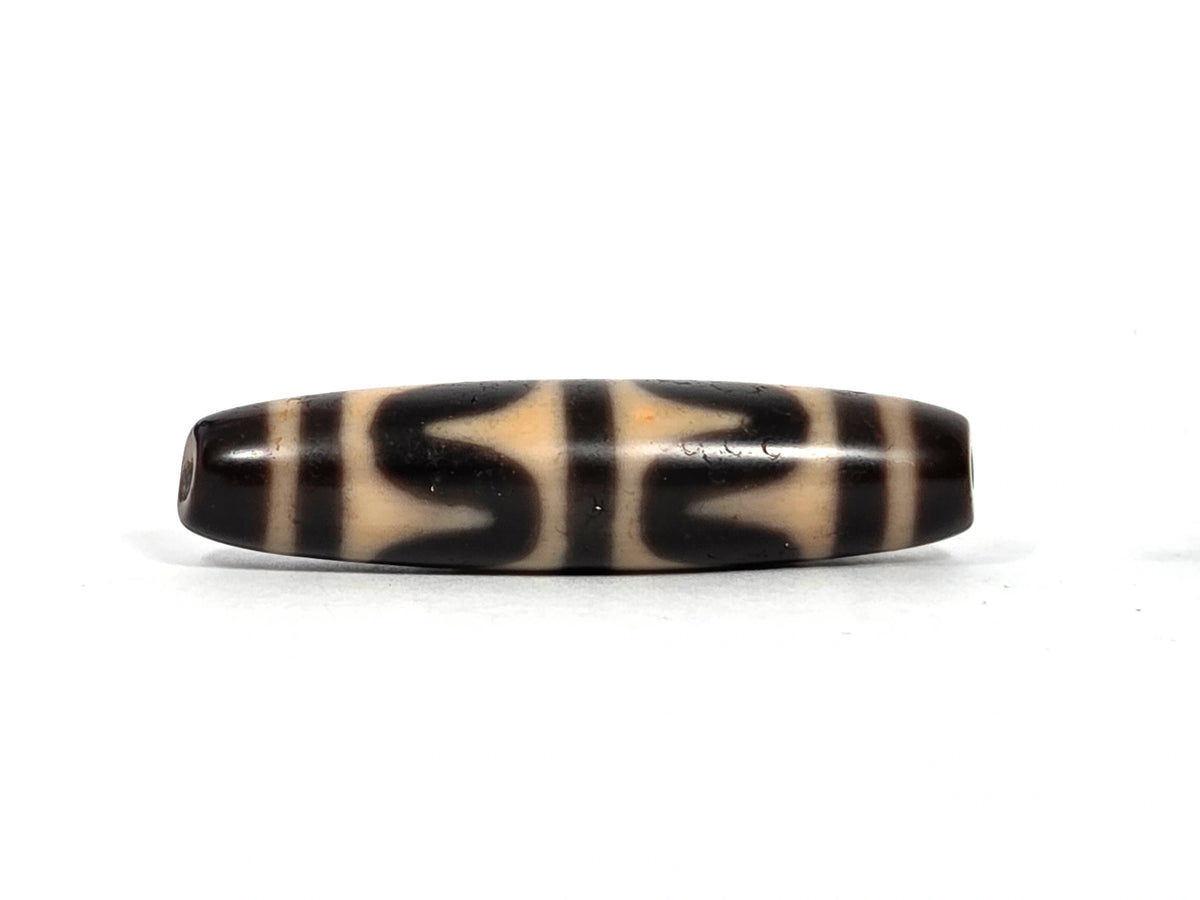 Second lateral profile of antique Tibetan double wave dzi bead showing reverse face with dark brown and black wave motif panels on warm honey-tan agate, 49.7 mm