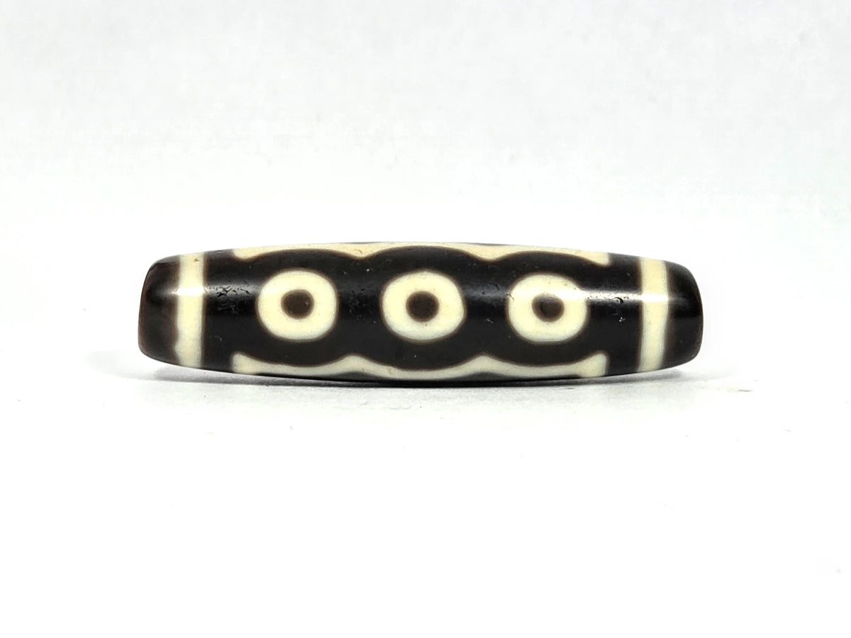 Antique Tibetan five-eye dzi bead (AT-100826-5E), three-eye face showing three cream-white eye rings in a row connected by undulating wave lines on deep dark brown agate, 49.4 mm, 200–400 years old