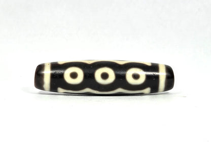 Antique Tibetan five-eye dzi bead (AT-100826-5E), three-eye face showing three cream-white eye rings in a row connected by undulating wave lines on deep dark brown agate, 49.4 mm, 200–400 years old
