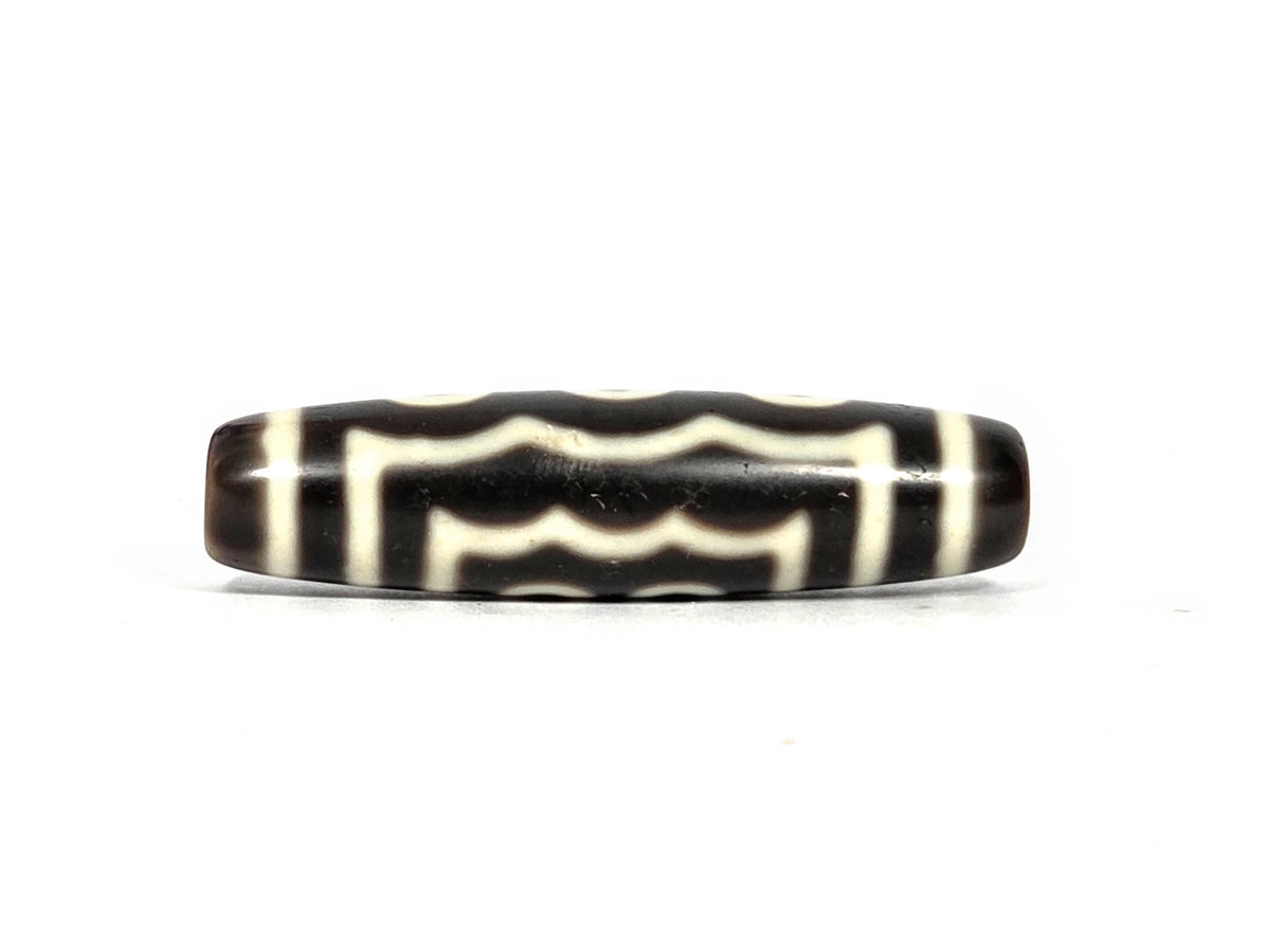 Wave face of antique Tibetan five-eye dzi bead showing three horizontal cream-white wavy lines running the full length of the face on dark brown agate ground, 49.4 mm