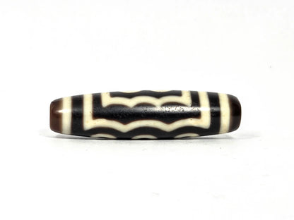 Second wave face of antique Tibetan five-eye dzi bead showing four to five stacked undulating cream-white wave lines on dark brown-black agate, 48.9 mm × 12.7 mm