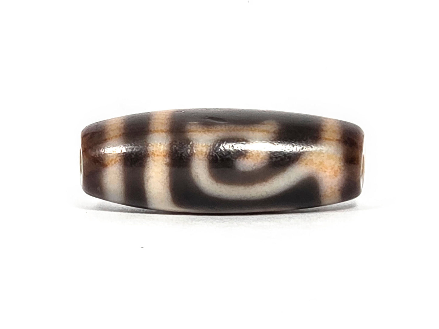 At-082326-GTBS antique Green Tara dzi bead 30.3×11.3mm, Face A showing cursive scroll motif on dark brown ground, cream lines with warm reddish-orange tinge, unretouched