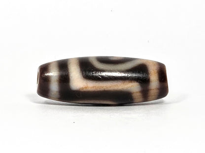 At-082326-GTBS antique Green Tara dzi bead 30.3×11.3mm, turn view showing Tara scroll continuing around shoulder with warm cream-honey zones, unretouched