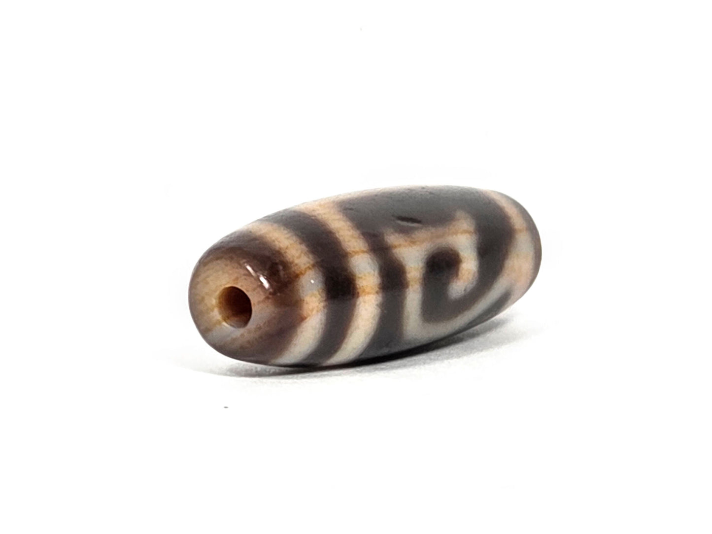 At-082326-GTBS antique Green Tara dzi bead 30.3×11.3mm, opposite angled drill-end view showing warm honey agate end cap and Tara scroll on body, unretouched
