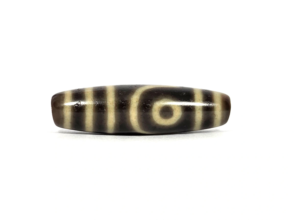 Second face of antique Tibetan two eye dzi bead AT-102126-2E — second cream eye framed by a curved line, positioned toward the opposite end from the first eye, on dark brown agate, 41.5 mm × 11.7 mm