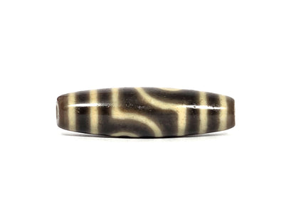 Opposite side view of antique Tibetan two eye dzi bead AT-102126-2E showing the mirror-image stepped S-curve divider between the two eye frames, dark brown agate ground, cream end bands