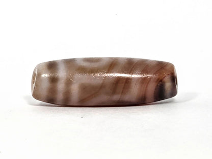 At-080426-2EBS antique two eye dzi bead 38.0×13.1mm, turn view showing cream-beige and brown agate banding running length of body, unretouched