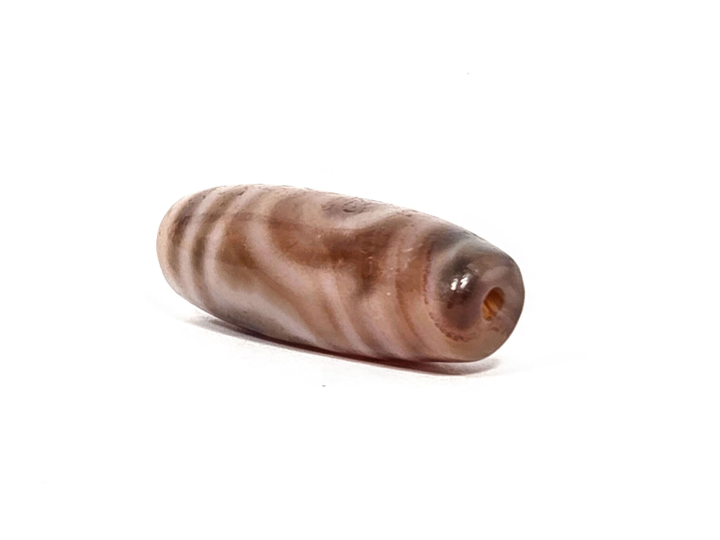 At-080426-2EBS antique two eye dzi bead 38.0×13.1mm, angled drill-end view showing cream-white agate end cap and banding, unretouched