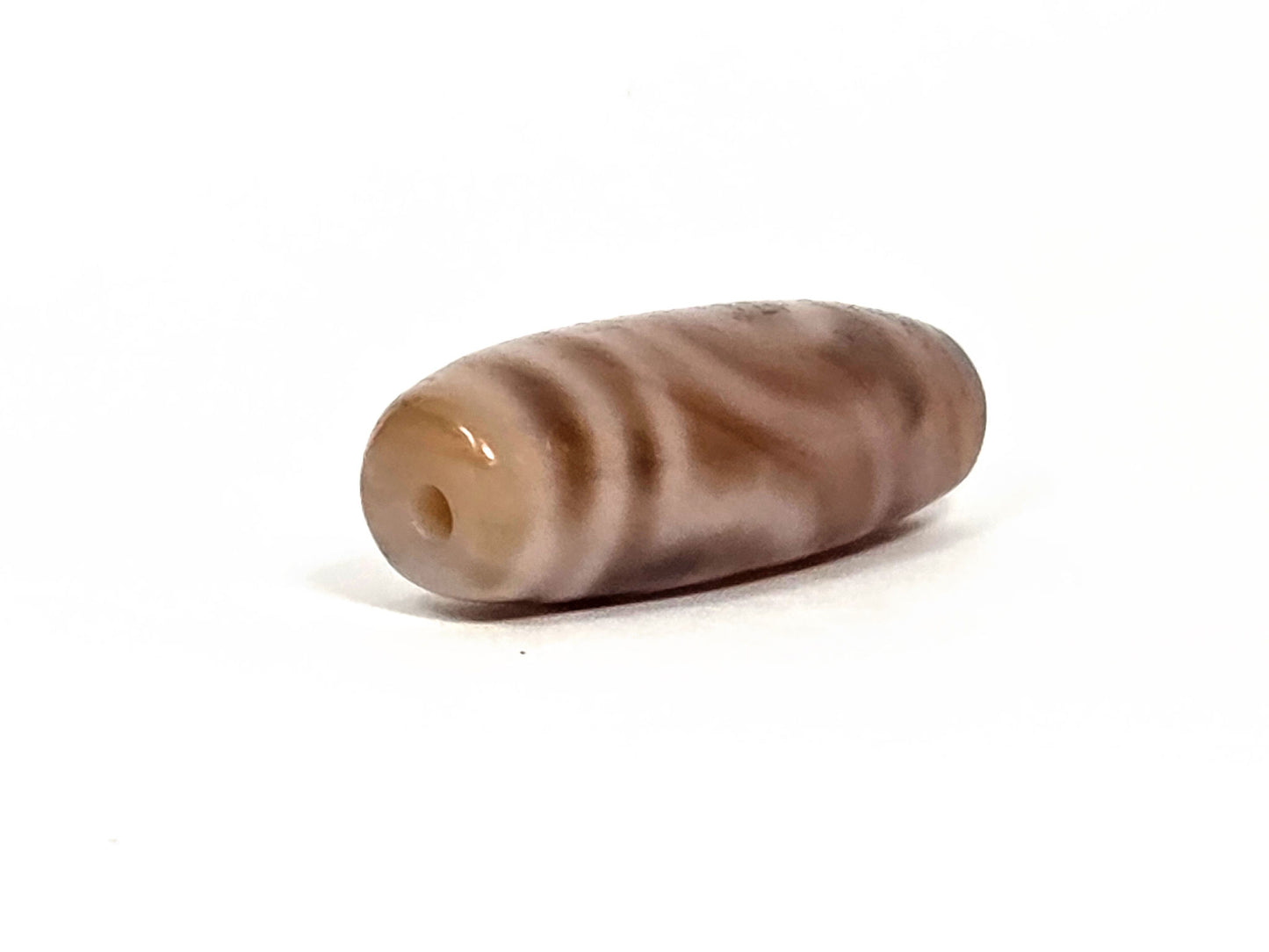 At-080426-2EBS antique two eye dzi bead 38.0×13.1mm, opposite drill-end angled view showing cream-white end cap and barrel profile, unretouched