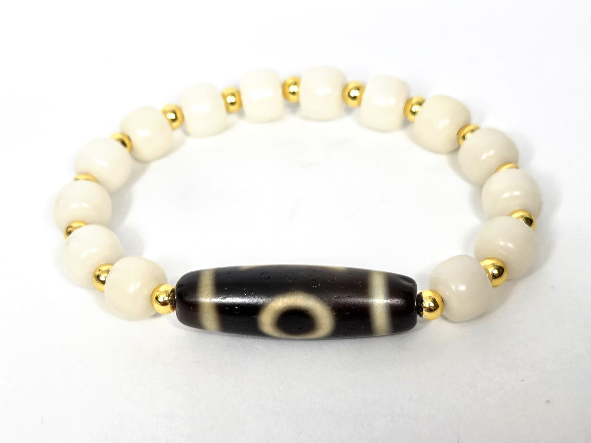 Dzi bracelet with black agate tube bead featuring white eye motifs, white bodhi root beads, and gold spacers