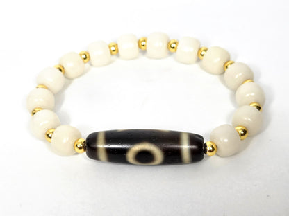 Dzi bracelet with black agate tube bead featuring white eye motifs, white bodhi root beads, and gold spacers