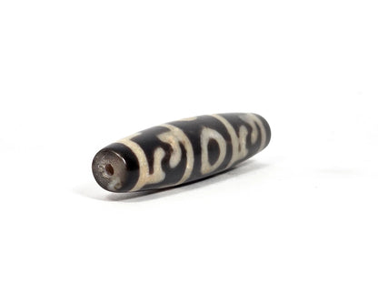 Opposite end view of new Taiwan three-eye and Guru Rinpoche paraphernalia dzi bead showing second drill hole and tapered black agate tip with cream-white motif lines continuing to the end