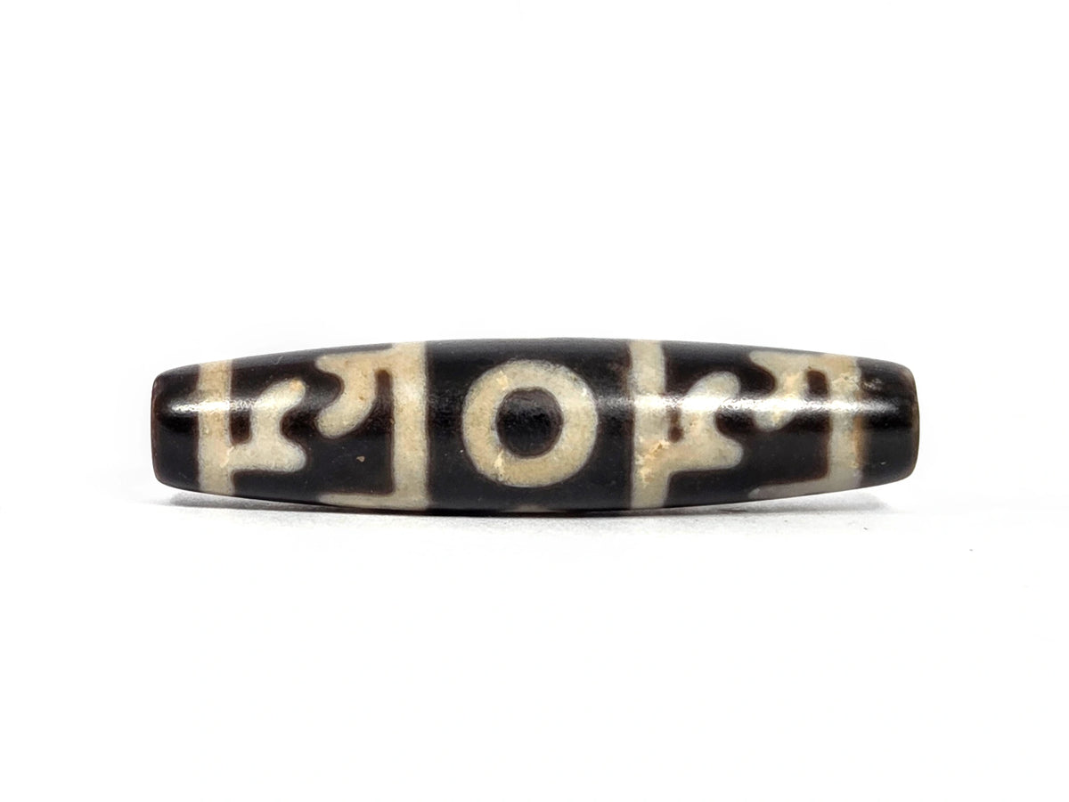New Taiwan three-eye and Guru Rinpoche's ritual paraphernalia dzi bead (N-092726-GRP3E), first lateral profile showing three-panel composition with central eye and flanking paraphernalia elements on pitch-black agate, 58 mm