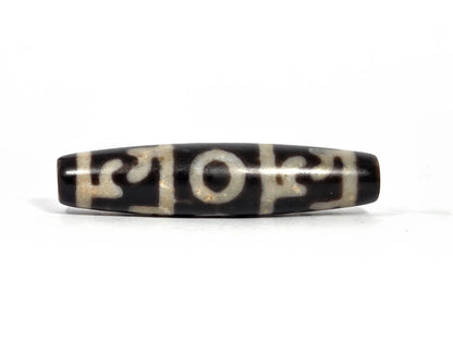 Second lateral profile of new Taiwan three-eye Guru Rinpoche paraphernalia dzi bead showing reverse face with central eye ring and cream-white curvilinear paraphernalia motifs on dark brown-black ground