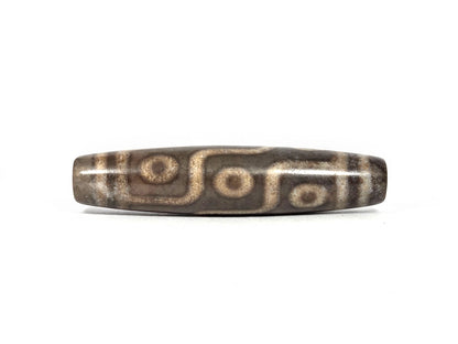 New nine-eye dzi bead N-101026-9E, first lateral profile showing all nine eyes with cream-tan rings and dark centers connected by S-curve maze-line network on deep charcoal-grey agate ground, 58.5 mm