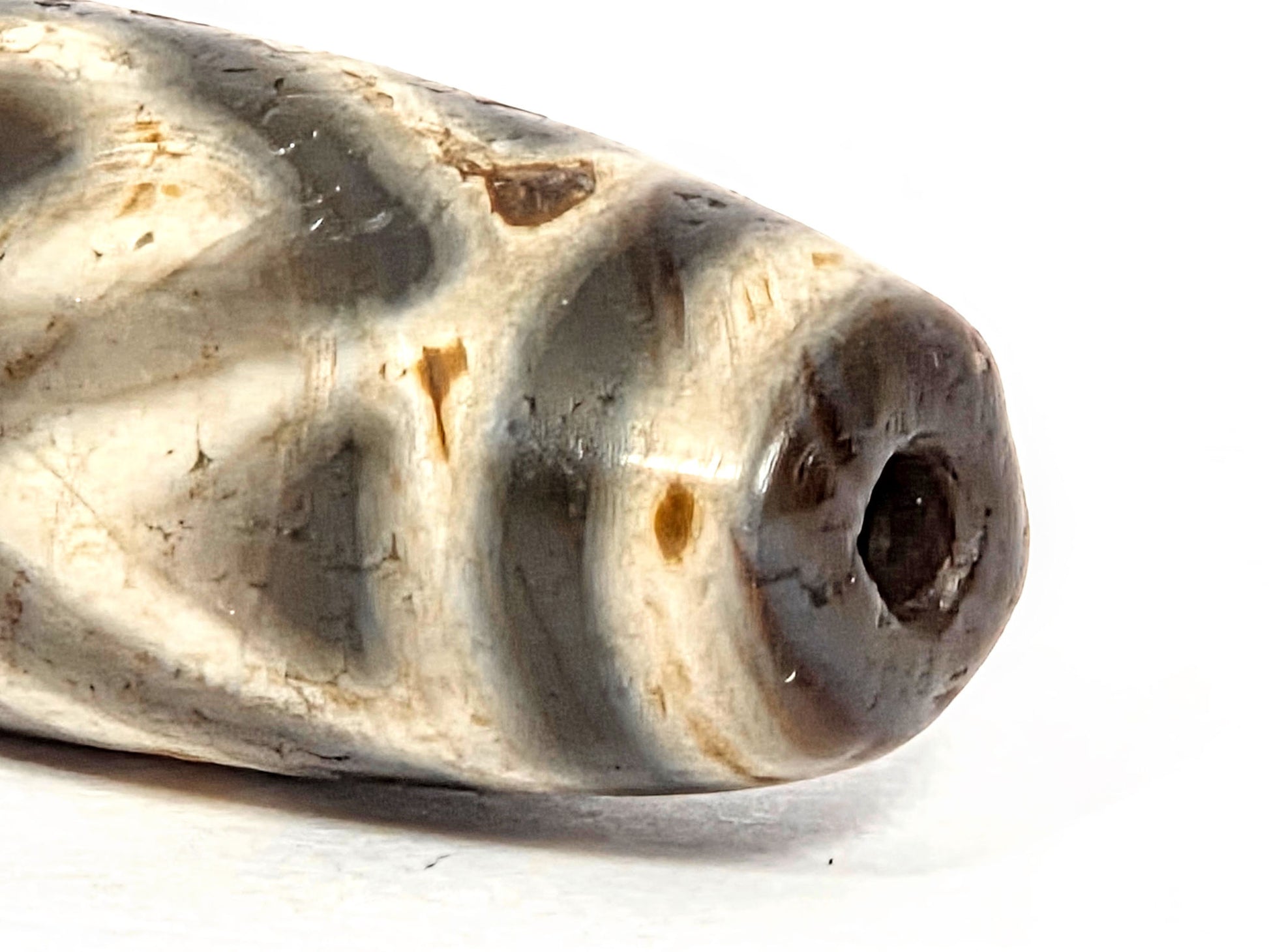 Ancient Three Diamond Eye and Tiger Tooth Dzi bead held in hand against green background — scale reference, 36.3mm genuine Tibetan amulet