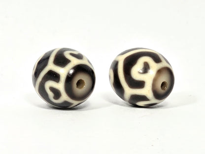 Drill hole end view of antique Tibetan Six Eye Lotus round Dzi bead pair showing swirl and lotus petal pattern surrounding natural agate drill holes — unretouched photo — Ancient Dzi Shop
