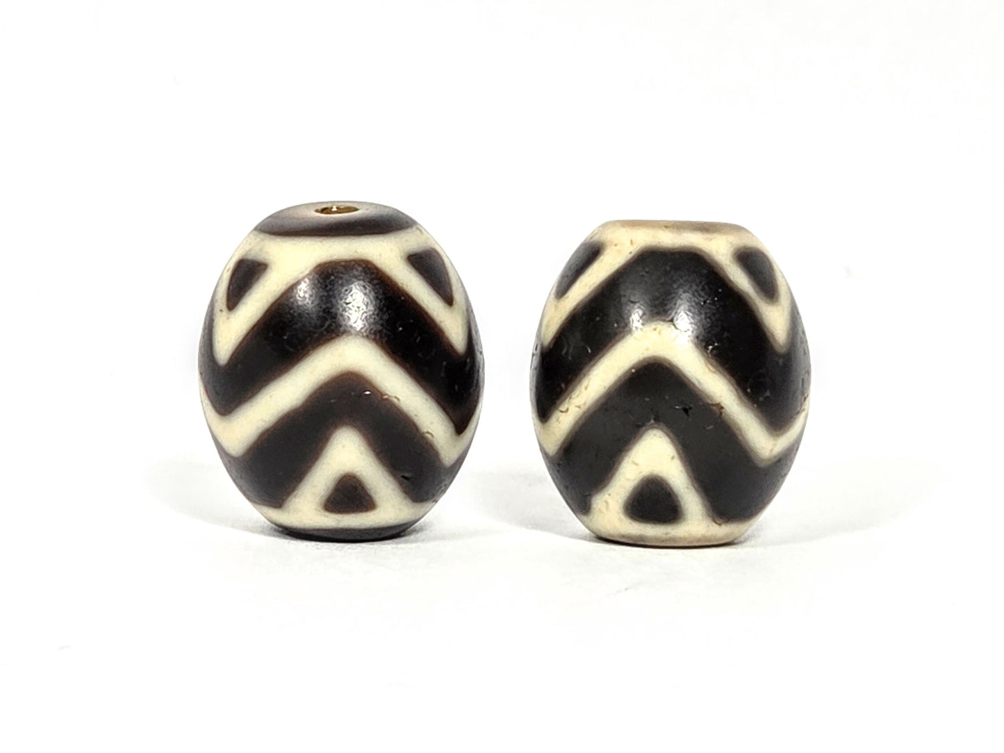 At-070626-TTW pair rotated face 3, Bead A ivory-cream, Bead B stark white motif contrast, very dark brown ground, unretouched