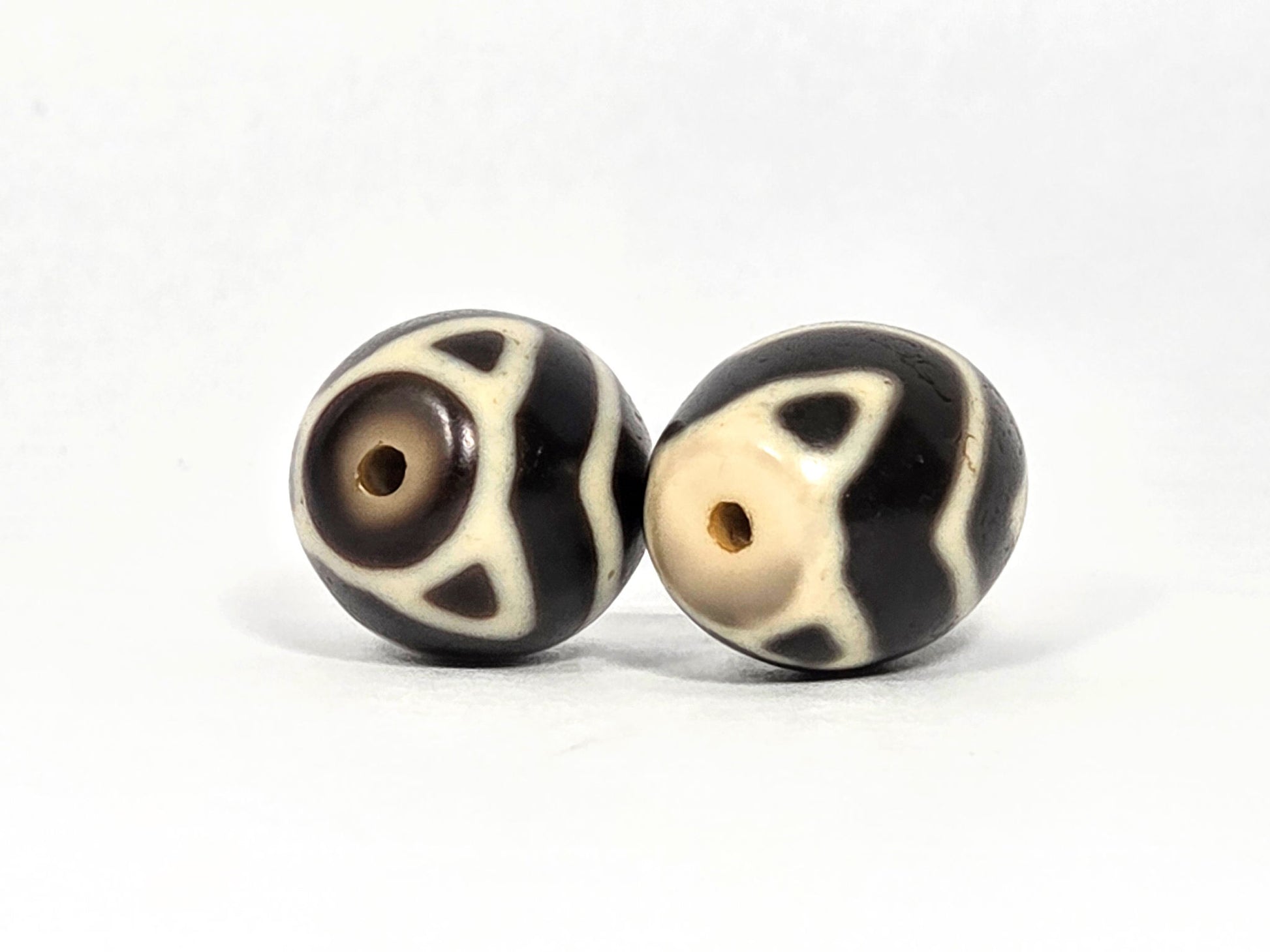 At-070626-TTW opposite drill-end pair, tiger tooth triangular tips, very dark brown agate, cream motif lines, unretouched