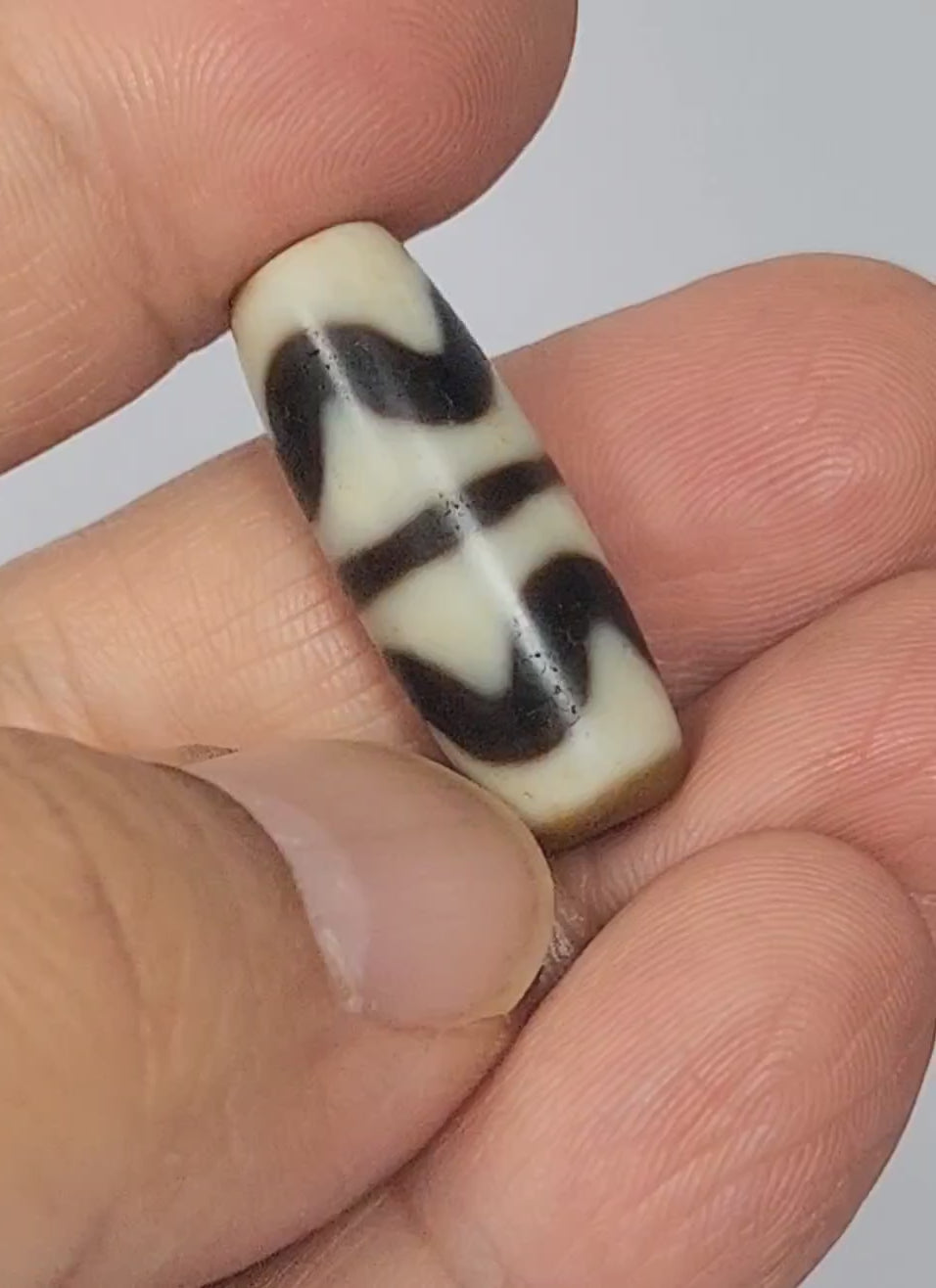Video of antique Tibetan Double Wave dzi At-072325-DW5 rotating 360°, two interlocking cream wave forms on warm brown agate, compact 28.4mm × 10.6mm torpedo, 200–300 yrs, unretouched