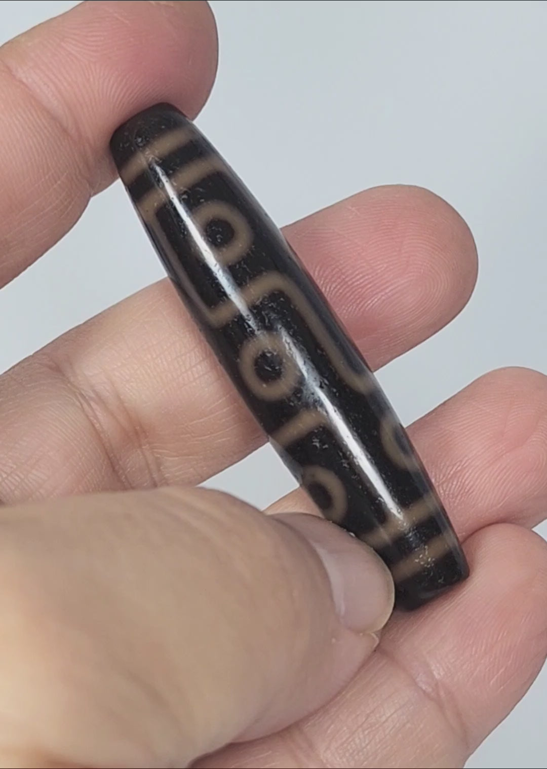 Video of antique Tibetan nine eye dzi At-012325-9E4 rotating 360°, amber-orange rings on deep dark brown agate, full 59.0mm × 13.2mm torpedo, King of motifs, unretouched footage