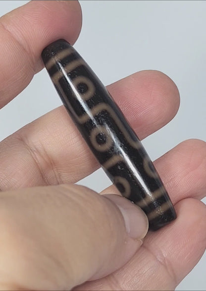 Video of antique Tibetan nine eye dzi At-012325-9E4 rotating 360°, amber-orange rings on deep dark brown agate, full 59.0mm × 13.2mm torpedo, King of motifs, unretouched footage