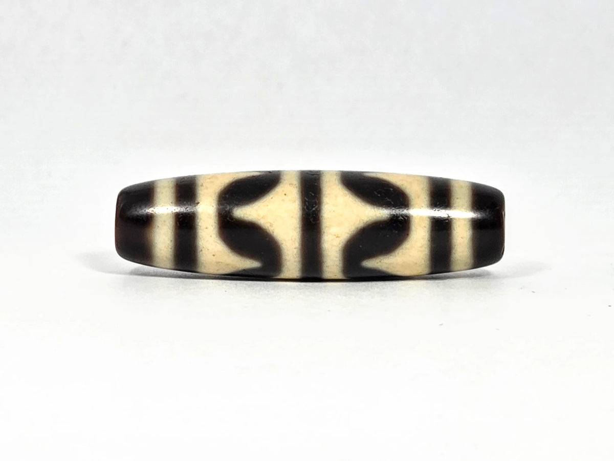 Antique Tibetan double wave dzi bead (AT-092826-DW2), first lateral profile showing bold black double wave forms in three panels on cream-white agate ground, 40.4 mm, 200–400 years old